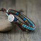 Multistrand bracelet with tree of life charm on a wooden surface