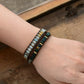 Close-up of a wrist wearing a beaded bracelet on a wooden surface