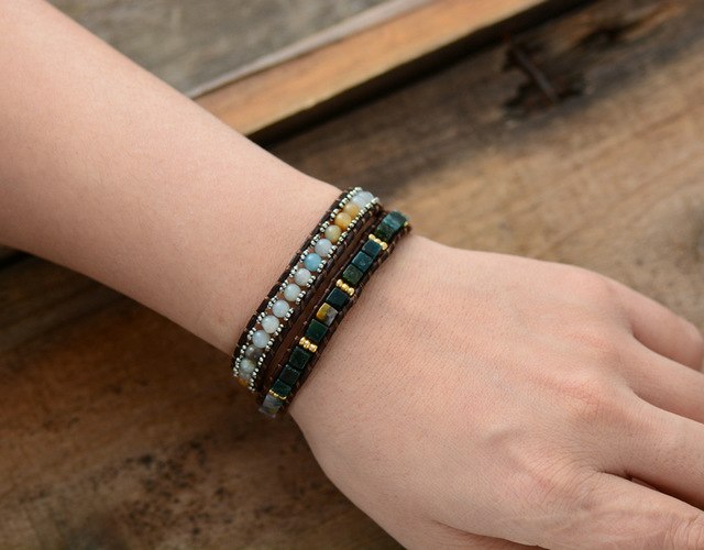 Close-up of a wrist wearing a beaded bracelet on a wooden surface