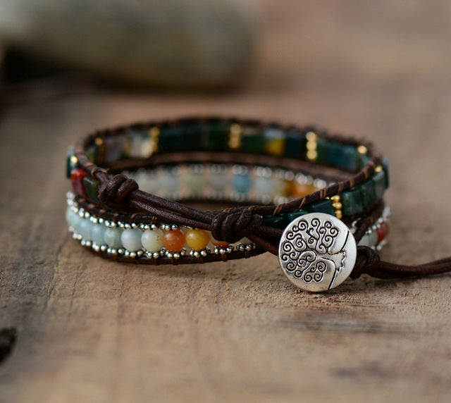 Multistrand beaded bracelet with a tree of life charm on a wooden surface
