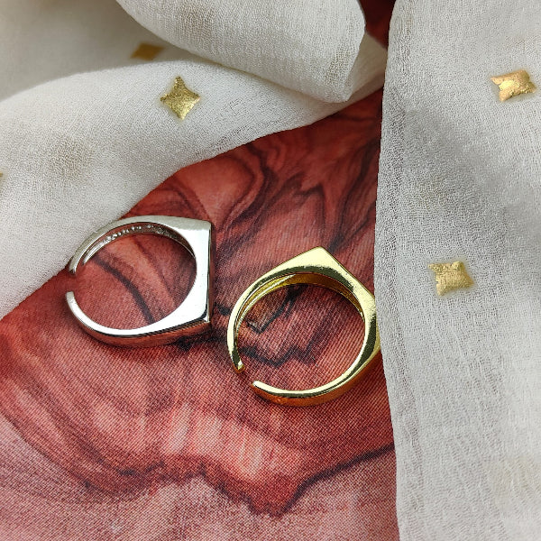 Two gold rings on a textured red and beige surface with decorative elements.
