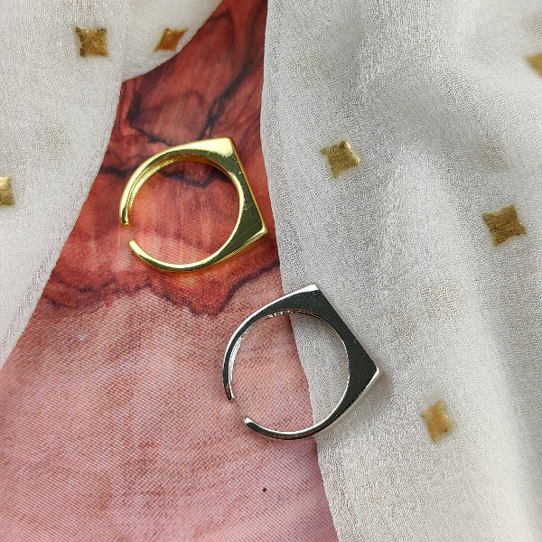 Two gold and silver cat-shaped rings on a textured fabric background