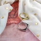 Two rings, one gold and one silver, on a textured fabric background.