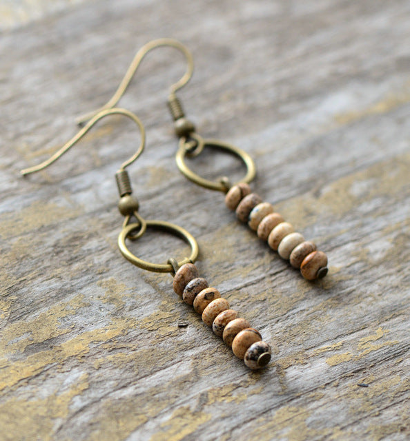 Beaded earrings with bronze hooks on a wooden surface