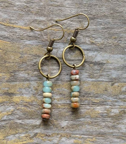 Pair of gold hoop earrings with bead extensions on a wooden surface