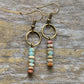 Pair of earrings with gold rings and bead drops on a wooden surface