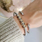 Close-up of a wrist wearing gold and silver bracelets with a blurred background