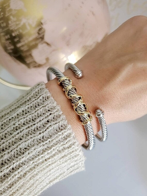 Close-up of a wrist wearing gold and silver bracelets with a blurred background