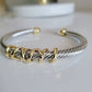 Bangle with gold and silver cable design on a white background