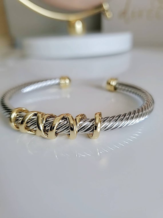 Bangle with gold and silver cable design on a white background