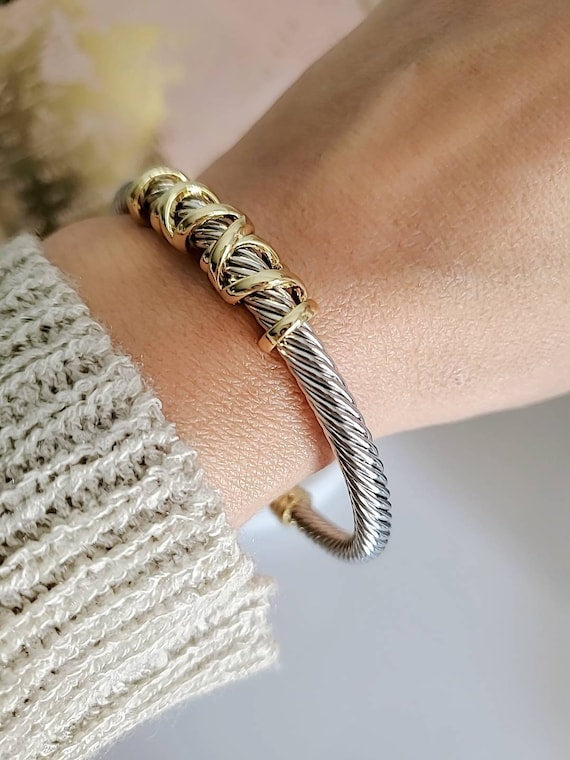 Gold and silver braided bracelet on a wrist with a blurred background