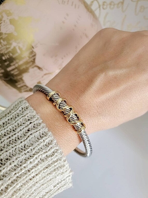 Gold and silver braided bracelet on a wrist with a blurred background
