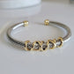 Bracelet with gold and silver cable design on a white background