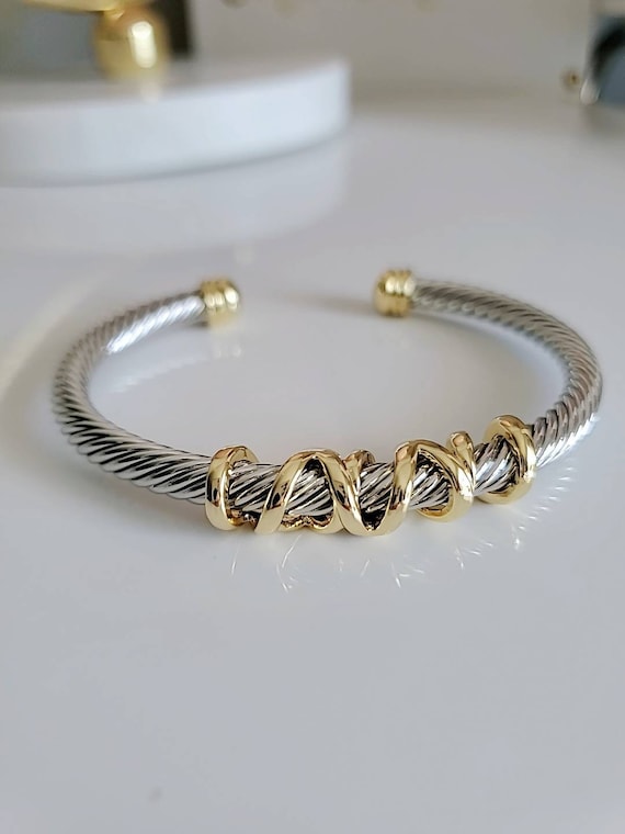 Bracelet with gold and silver cable design on a white background