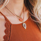 Close-up of a person wearing multiple necklaces with a brown top.
