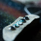 Close-up of a guitar with metallic and turquoise inlays on a blurred background