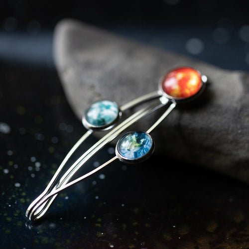 Silver brooch with colorful gemstones on a dark textured surface