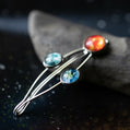 Silver brooch with colorful gemstones on a dark textured surface