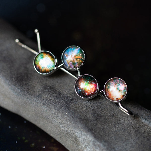 Hairpin with galaxy-themed ceramic discs on a dark stone surface