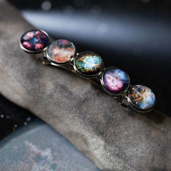 Barrette with galaxy-themed hair clips on a stone surface