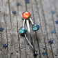 Three hair pins with celestial designs on a wooden surface with star decorations.