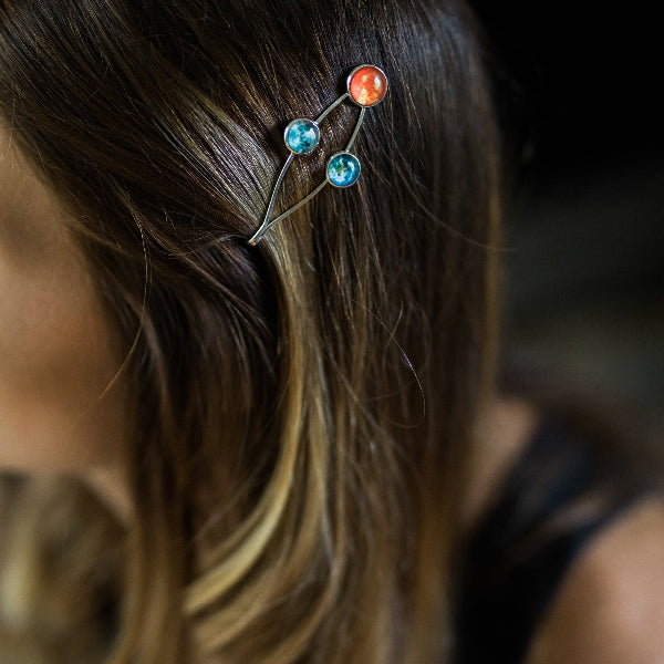 Close-up of a hairpin with colorful gemstones in a person's hair.