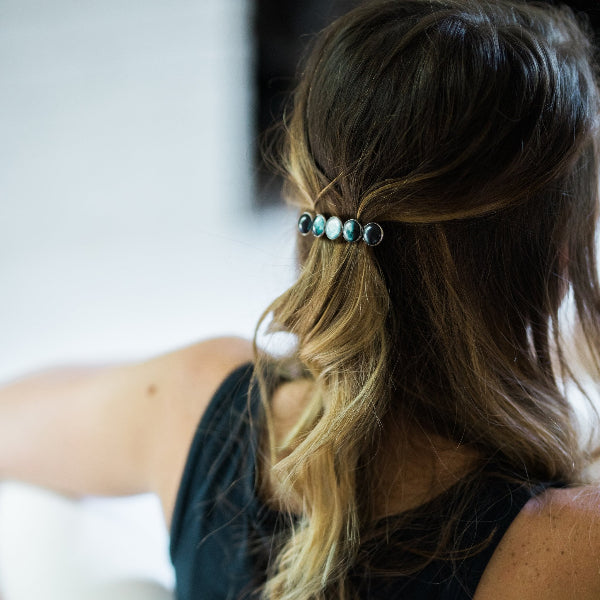 Person with a hair accessory featuring beads in a blurred indoor setting
