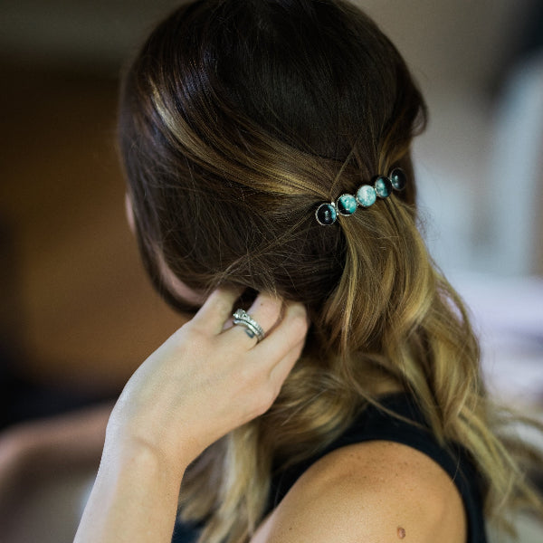 Person adjusting hair with decorative hairpins, blurred background