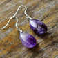Purple teardrop earrings on a wooden surface