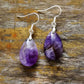 Pair of purple teardrop earrings on a wooden surface