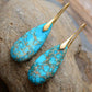 Turquoise earrings with gold hooks on a rock