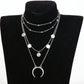 Layered silver necklace with moon pendant on a black bust