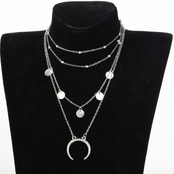 Layered silver necklace with moon pendant on a black bust