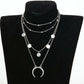 Layered silver necklace with circular pendants on a black mannequin bust.