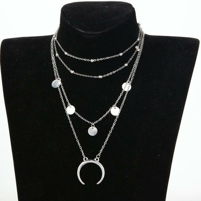 Layered silver necklace with circular pendants on a black mannequin bust.