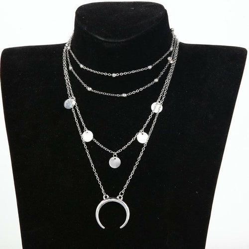 Layered silver necklace with circular pendants on a black mannequin bust.