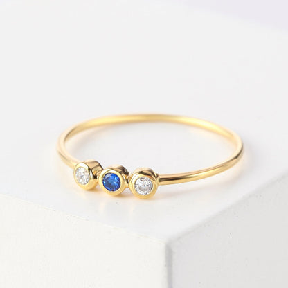 Gold ring with three gemstones on a light background