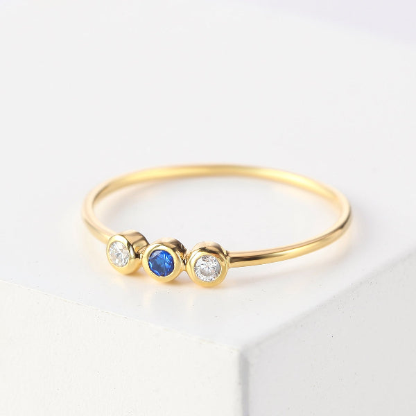 Gold ring with three gemstones on a light background