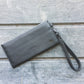 Gray wristlet clutch on a wooden surface with 'veganmian.com' branding.