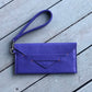 Purple clutch bag with a strap on a wooden surface