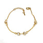 Gold bracelet with spherical beads on a white background