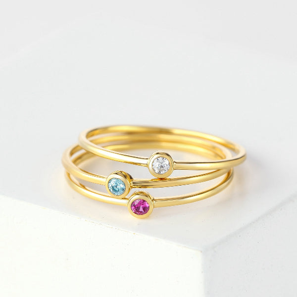 Three gold rings with gemstones on a white background