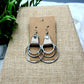 Silver hoop earrings on a brown card with a natural background