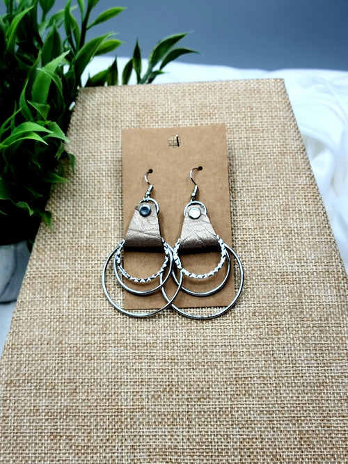Silver hoop earrings on a brown card with a natural background