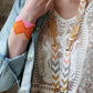 Person wearing a colorful necklace with geometric patterns and a matching bracelet.