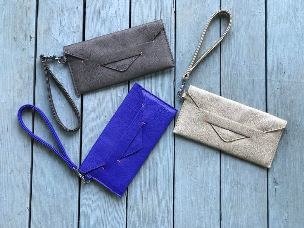 Four handbags in gray, blue, and beige on a wooden surface