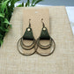 Pair of earrings on a beige card with a green leafy background