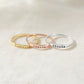 Three rings with engraved names on a light background