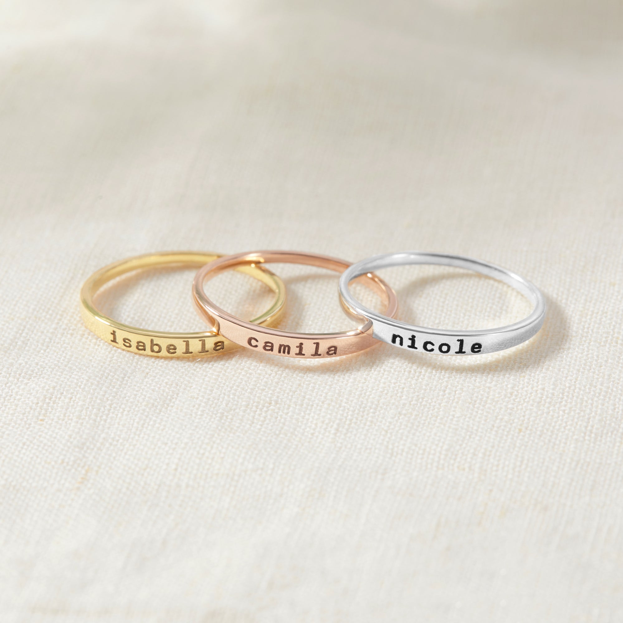 Three rings with engraved names on a light background