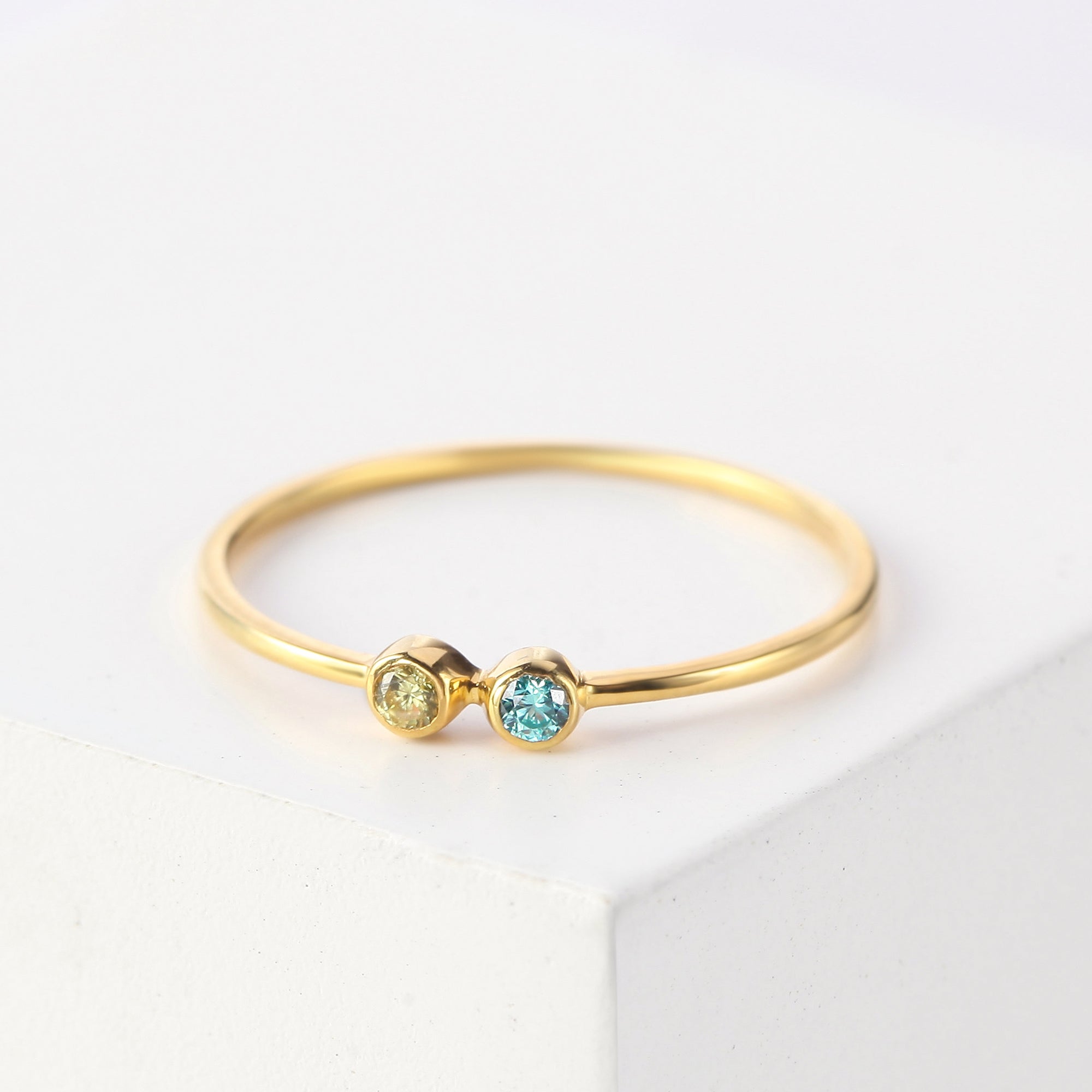 Gold ring with two gemstones on a white background